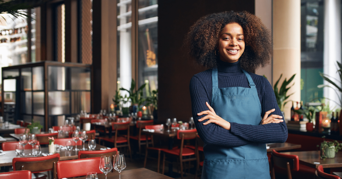 Smiling restaurant owner in an apron, showcasing confidence and readiness to boost business with unsecured bad credit loans.