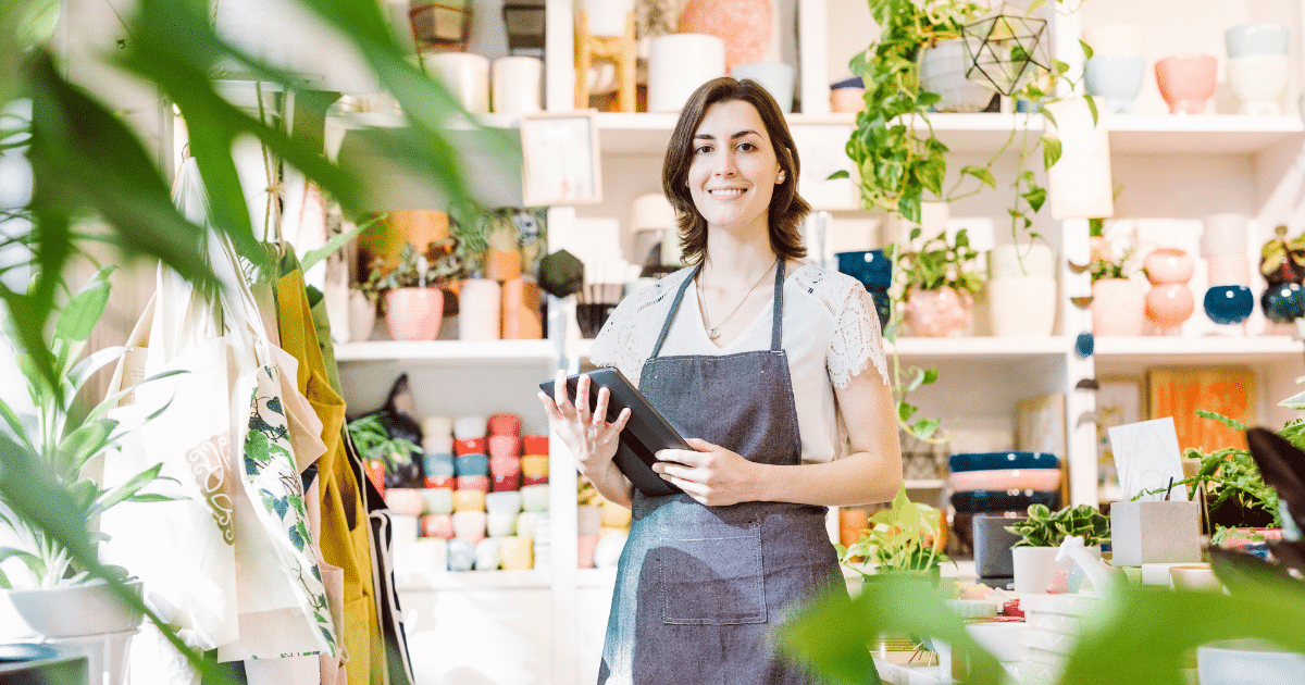Smiling business owner in a plant shop, showcasing flexible financing options for small businesses.