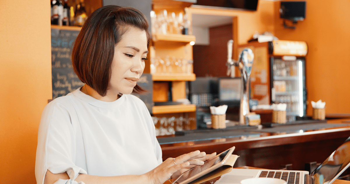 Woman using mobile payment solutions in a cafe, showcasing the convenience of digital transactions for businesses.