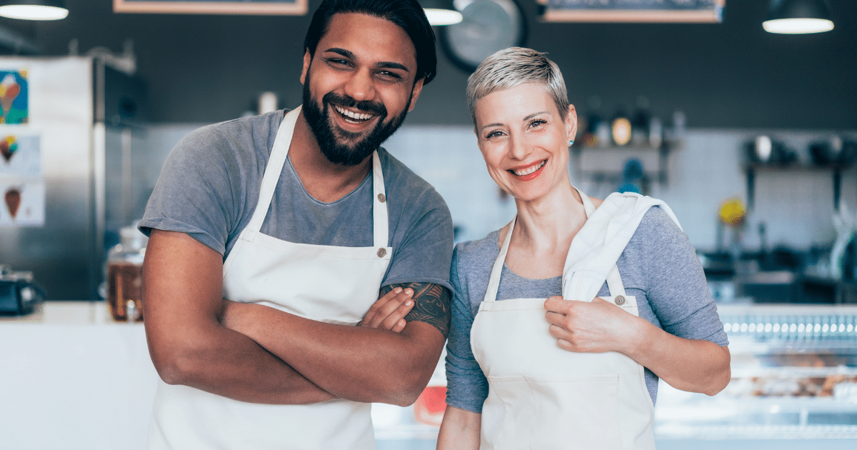 Smiling business owners in aprons representing small business growth and financing solutions for success.