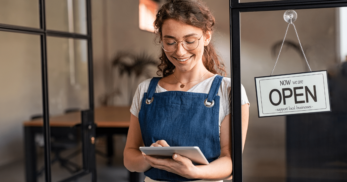 Smiling woman using a tablet in a business setting, highlighting the importance of mobile accessibility for emails and websites.