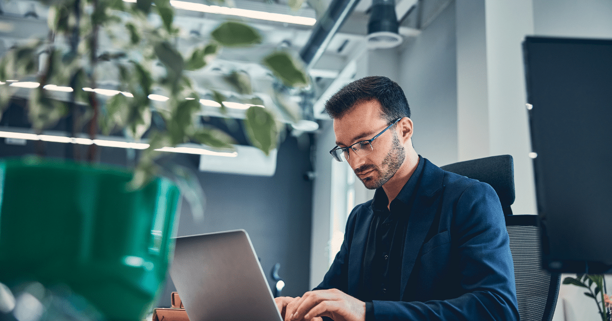 Professional man working on a laptop in a modern office, emphasizing employee engagement strategies in business.