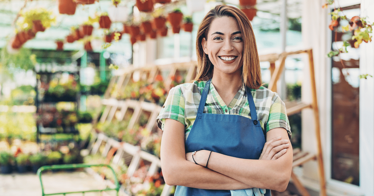 Smiling woman in an apron at a garden center, representing customer service and business growth strategies.