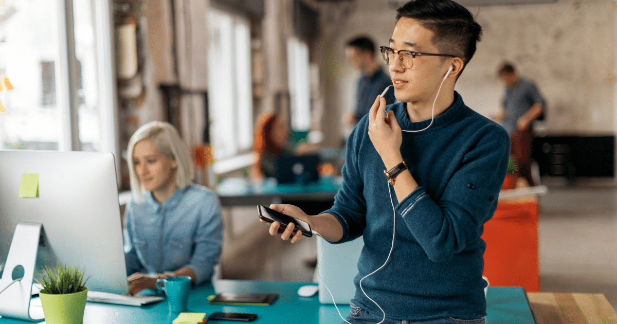 Young professional in a modern office, focused on smartphone, highlighting small business tax tips and financial success.