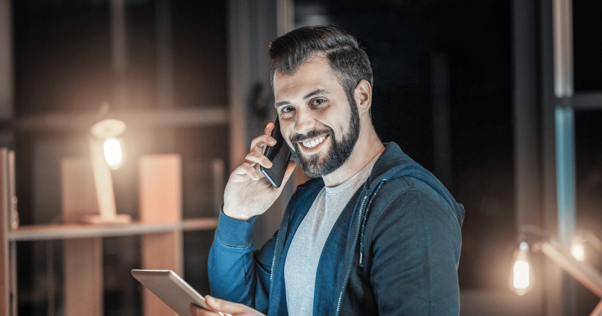 Smiling man on phone with tablet, representing effective credit building strategies without debt.