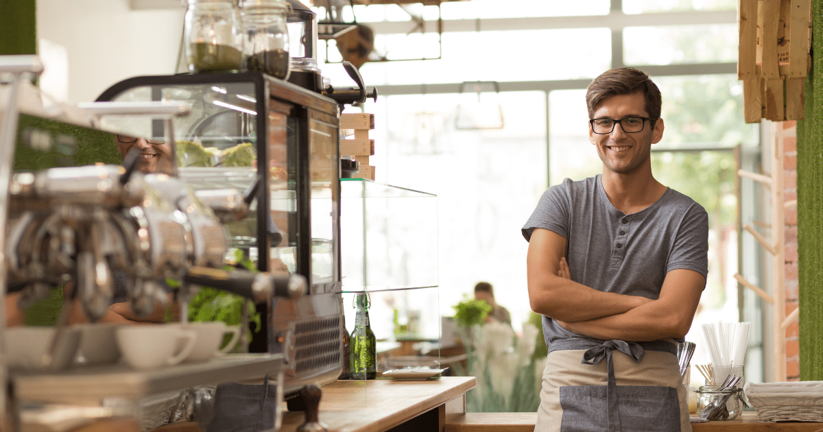 Small business owner smiling in a cafe, highlighting financial success and avoiding pitfalls in 2024.