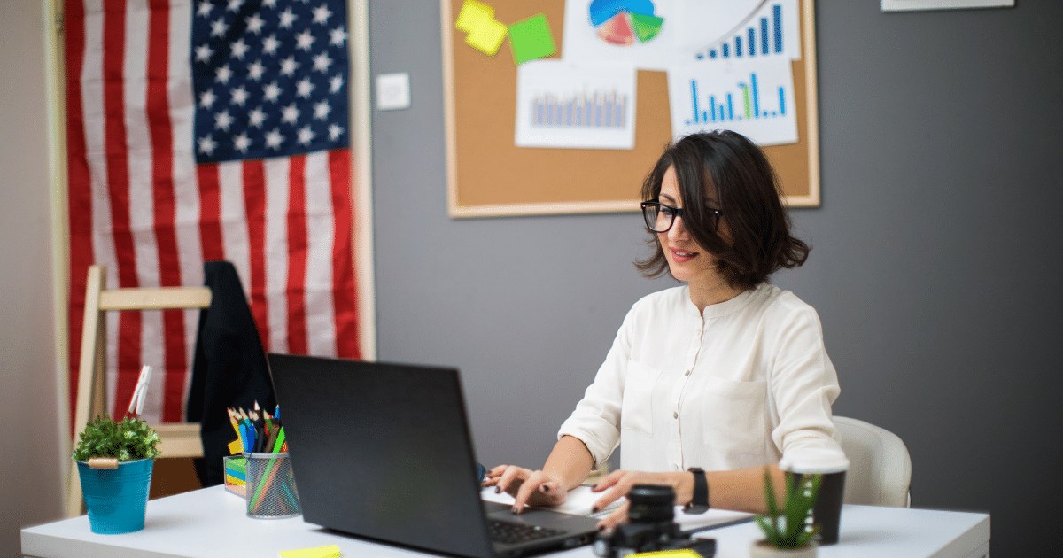 Businesswoman working on a laptop in an office with financial charts, preparing for a small business loan or credit application.