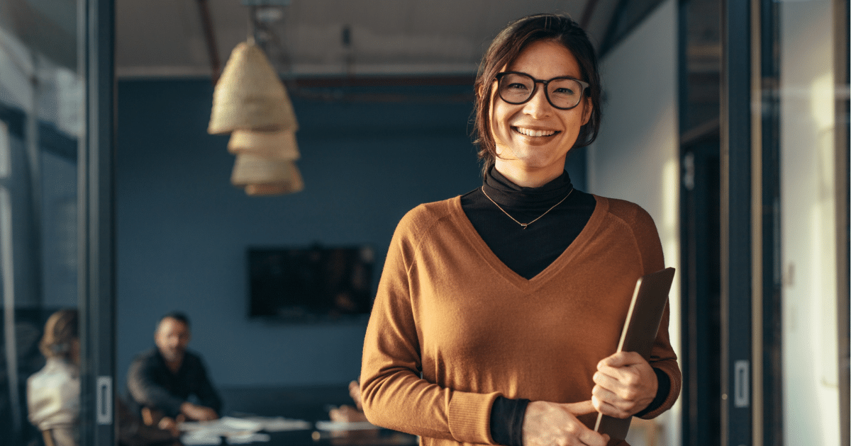 Smiling businesswoman in an office promoting cost-effective social media marketing for small businesses.