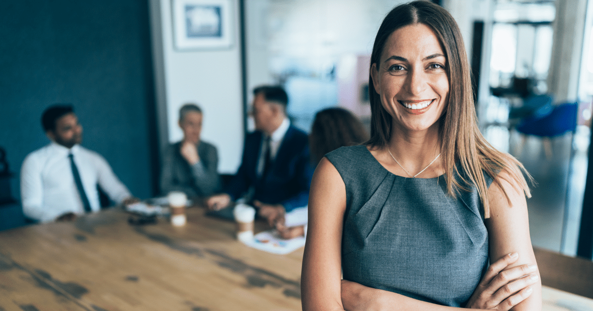 Businesswoman smiling confidently in a modern office, highlighting business relocation strategies for profit maximization.