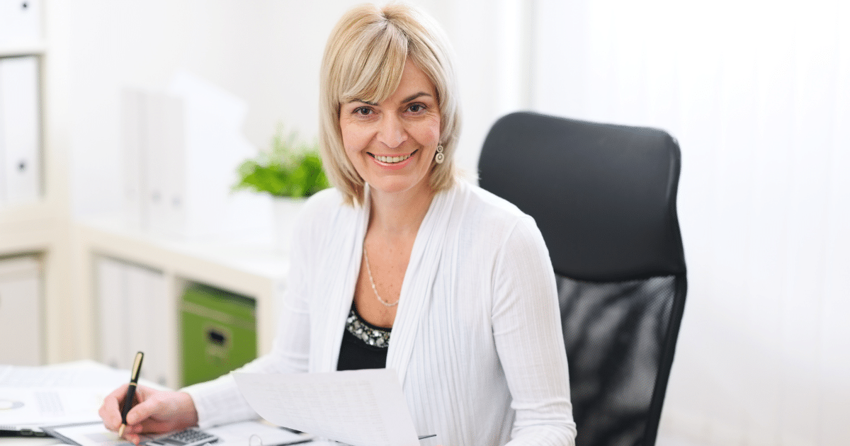 Smiling businesswoman reviewing documents in an office, emphasizing business credit profile scores and funding opportunities.