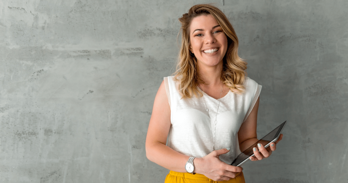 Smiling woman holding a tablet, representing small business loans and financial empowerment for entrepreneurs.