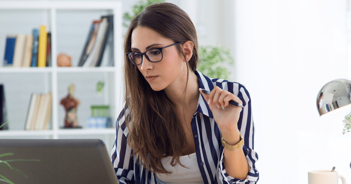Businesswoman analyzing strategies for success while working on a laptop in a modern office setting.