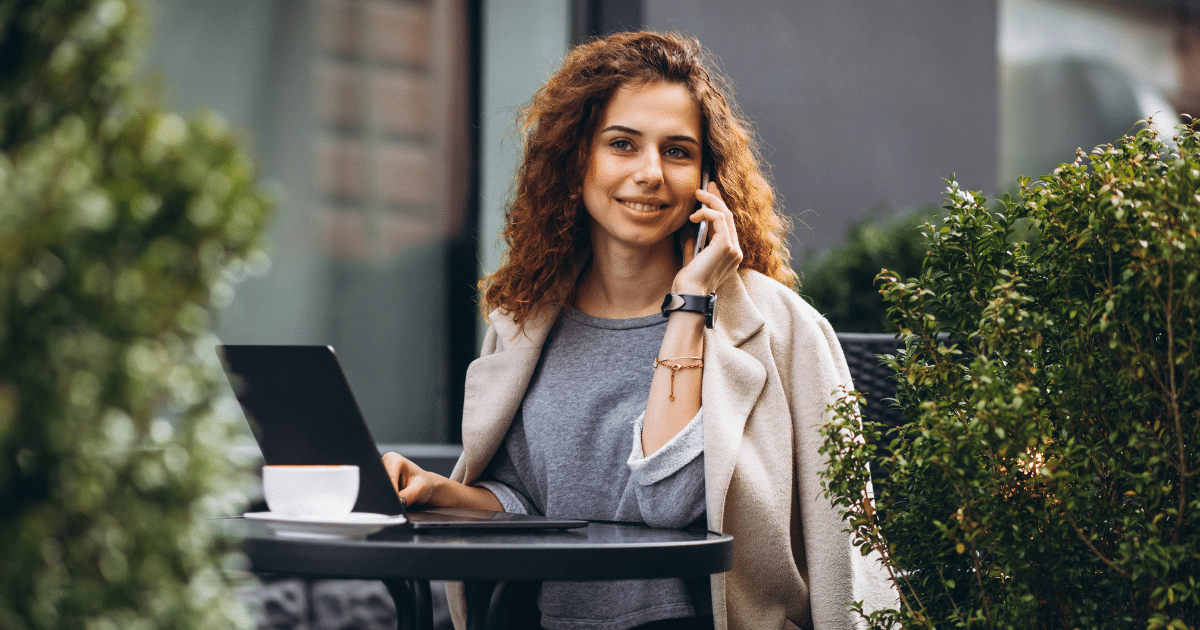 Young woman on a phone at a laptop, representing strategic blogging and dynamic content for SEO improvement.