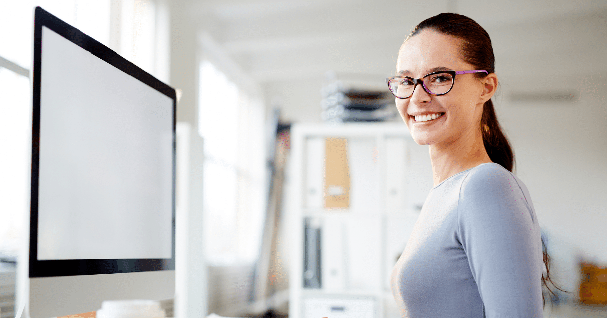 Smiling professional woman in an office, highlighting the importance of a healthy workforce for business success.