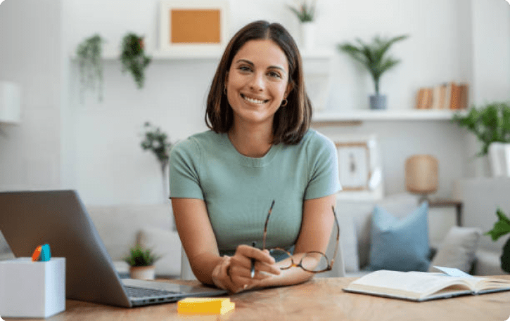 Smiling woman at a desk with a laptop, representing business financing and line of credit solutions.